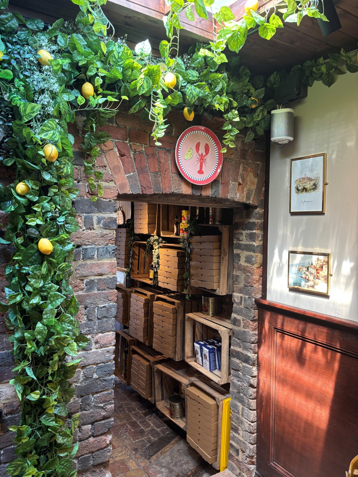 Lemon vines over rustic crate shelving stacked with pizza boxes